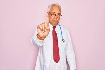 Middle age senior grey-haired doctor man wearing stethoscope and professional medical coat Pointing with finger up and angry expression, showing no gesture