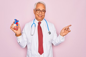 Middle age senior grey-haired cardiologist doctor man holding professional medicine heart very...
