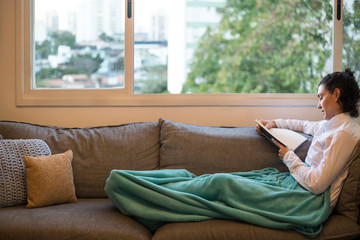 Mulher lendo no sofá, São Paulo, Brasil (Woman reading on the couch, Sao Paulo, Brazil), by Carol...