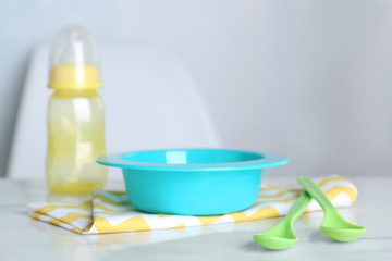 Set of plastic dishware on white table indoors. Serving baby food