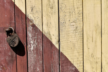 Mixed yellow and red wooden planks background with old lock.