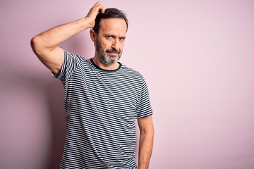 Middle age hoary man wearing casual striped t-shirt standing over isolated pink background confuse...