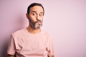 Obraz premium Middle age hoary man wearing casual t-shirt standing over isolated pink background making fish face with lips, crazy and comical gesture. Funny expression.