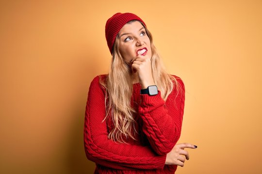 Young beautiful blonde woman wearing casual sweater and wool cap over white background Thinking worried about a question, concerned and nervous with hand on chin