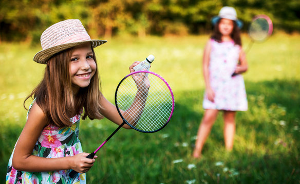 Childhood time. Two little girls playing badminton in the park
