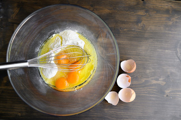 A transparent bowl with eggs and flour. Cooking cake. Selective focus.