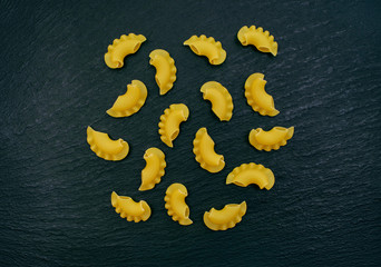 Raw pasta randomly scattered on a black background