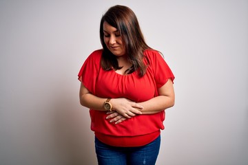 Beautiful brunette plus size woman wearing casual red t-shirt over isolated white background with hand on stomach because indigestion, painful illness feeling unwell. Ache concept.