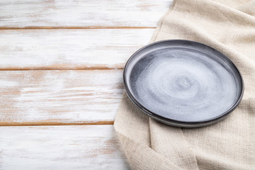 Empty gray ceramic plate on white wooden background and. Side view, copy space.