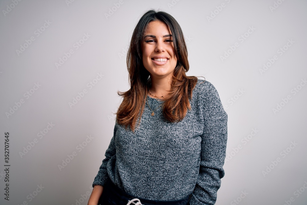 Wall mural Young beautiful brunette woman smiling happy and confident. Standing with smile on face wearing casual sweater over isolated white background