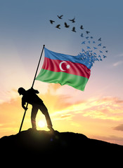 Azerbaijan flag turn to birds while being planted by a man on a hill during sunrise.