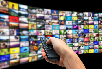 Streaming video services. Man using remote control to change channels on TV, closeup