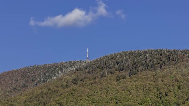 Timelapse of shadows and clouds moving on the slopes of Radhost hill overlooking the broadcast tower in a dense forest with moving shadows on the treetops in the Beskydy park area.