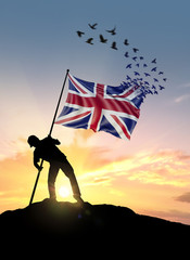 United Kingdom flag turn to birds while being planted by a man on a hill during sunrise.