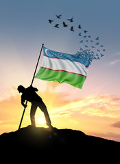 Uzbekistan flag turn to birds while being planted by a man on a hill during sunrise.