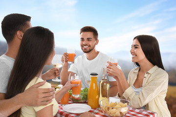 Group of friends having picnic at table in park