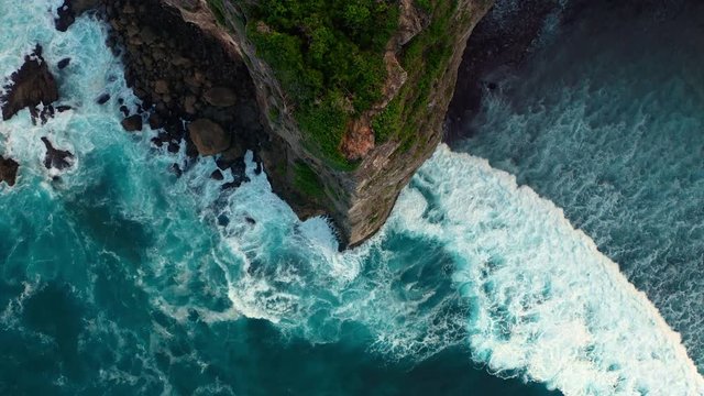 Aerial view from above on a tropical island and ocean waves crashing and foaming against sand beach. Bird's eye aerial shot of golden beach meeting deep blue ocean water. Tourism concept after covid.