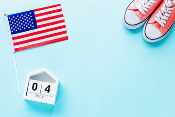 Fototapeta premium July 4th. Mockup of july 4 wooden color calendar and USA flag on blue background. Copy space for text. Independence Day Of America. Flat lay, top view, template