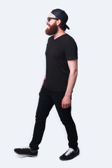Full length photo of bearded hispter man walking over white
