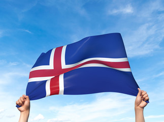 Two hands are holding a Iceland flag - flowing through the wind. 3D Illustration.