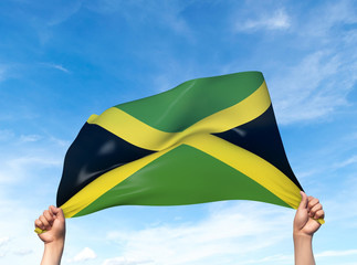 Two hands are holding a Jamaica flag - flowing through the wind. 3D Illustration.