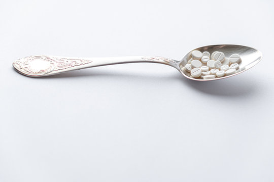 Medicine and health, treatment, pharmacy, coronavirus, pandemic, epidemic concept - layout one silver big tablespoon with different pills and capsules on a white background copy space.