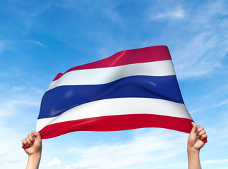 Fototapeta premium Two hands are holding a Thailand flag - flowing through the wind. 3D Illustration.