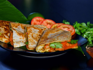 tortilla with vegetables on a black plate, pita with tomatoes, vegetarian sandwich with herbs, vegan food, traditional Indian bread with vegetables