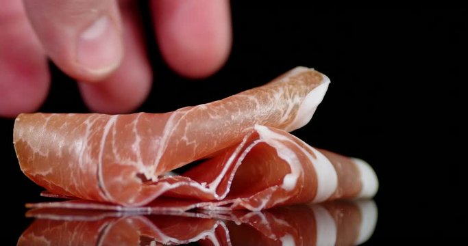 Man's hand puts on the table a piece of antipasto.