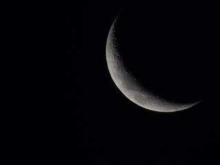 Crescent moon showing textures on the moon surface and craters