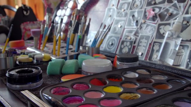 Pan of face painting kid with brushes and watercolours