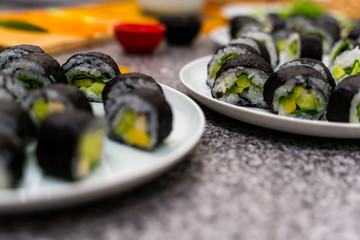 Close up vegan sushi rolls on the table, the ingredients are rice, avocado, cucumbers