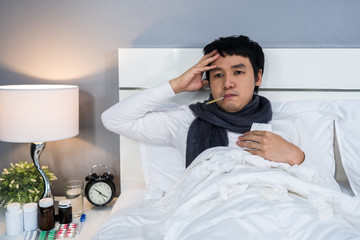 sick man is headache and using thermometer to checking his temperature in bed