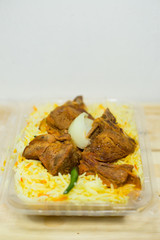 A plastic pack of lamb mandy rice on wood background. The best arabic food. Selective focus.