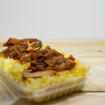 A plastic pack of lamb mandy rice on wood background. The best arabic food. Selective focus.