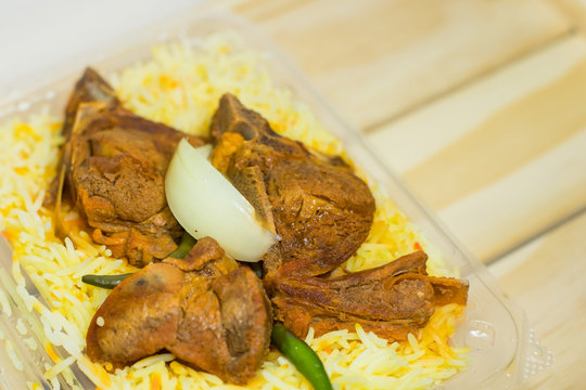 A plastic pack of lamb mandy rice on wood background. The best arabic food. Selective focus.