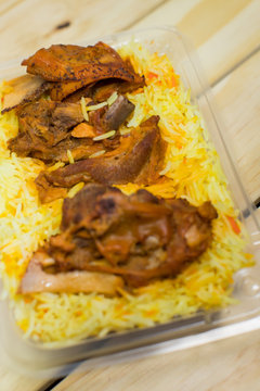 A plastic pack of lamb mandy rice on wood background. The best arabic food. Selective focus.
