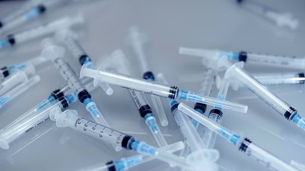 A lot of new plastic disposable syringes fall on light background. Closeup. Shallow depth of field. Slow mo, slo mo, slow motion, high speed camera
 - Powered by Adobe