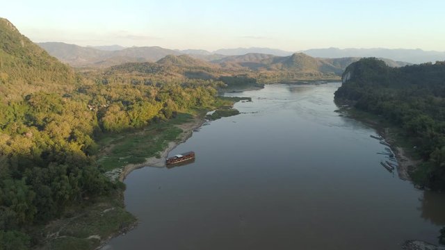 Aerial shot of river by mountains against sky, drone is moving backward - Mekong River, Laos