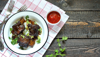 short ribs baked in an enamel plate.
long stewed meat. rustic style, wooden table, top view, copy space