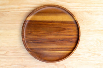 A round dish made of acacia wood and lacquered lacquer is placed on a rubber wood chopping block in the kitchen utensil concept.