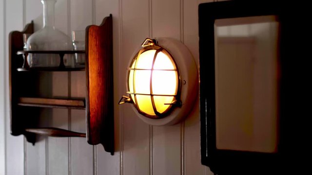 Old lamp and a shelf hanging on a wodden wall in a cabin on a traditional sailing ship. Camera panning movement. Shot in 4K.