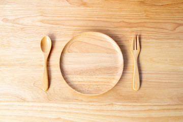 A round dish made of rubber wood and lacquer coated with spoons and forks and placed on a wooden chopping block in the kitchen utensil concept.
