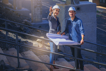 Structural engineer and architect working with blueprints discuss at the building structure, outdoor construction site