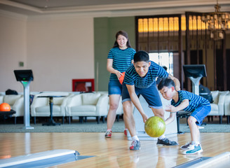 Father teaching son and family play bowling at bowling club on relax time, family activity on...