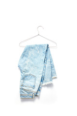 online shopping concept. beautiful blue jeans on a hanger of silver color. white frame background