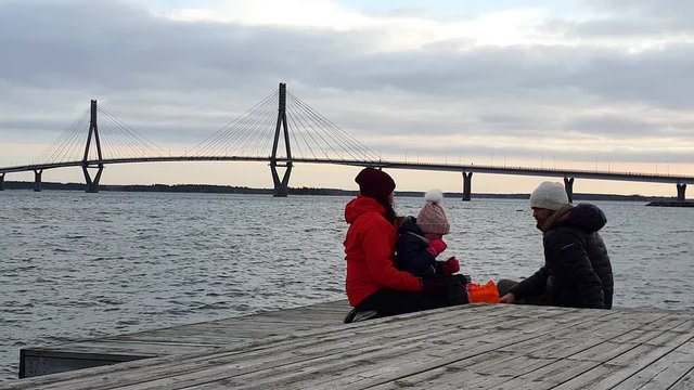 Establishing shot of long suspension bridge and hiking family having picnic