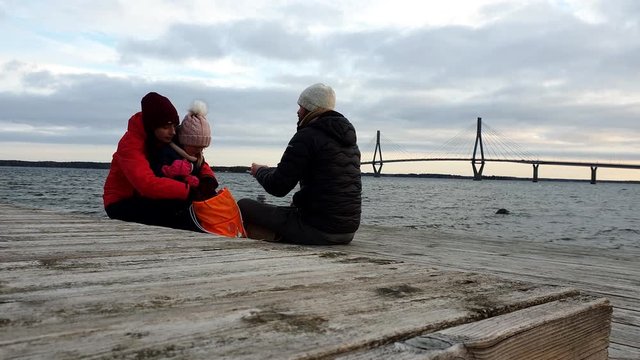 Hiking family having picnic and enjoying view of long suspension bridge