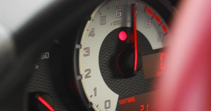Arrow of tachometer in car shows number of engine revolutions per second. Tachometer of a classic car with moving arrow on the gauge on dashboard, closeup view.