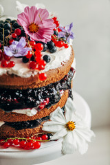 Closeup of a cake decorated with flowers and berries.